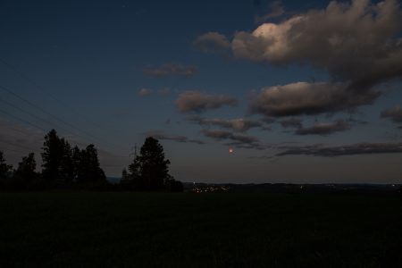 Úplné zatmění Měsíce 7. 9. 2025. Širší pohled objektivem Sigma 24 mm ukazuje, že oblačnost se sice rozpouštěla, ale Měsíc byl dlouho těsně u ní. Čas 20:16 SELČ. Alšovice, autor: Martin Gembec